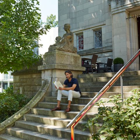 Mann der auf der Treppe vor der Kunsthalle sitzt und liest