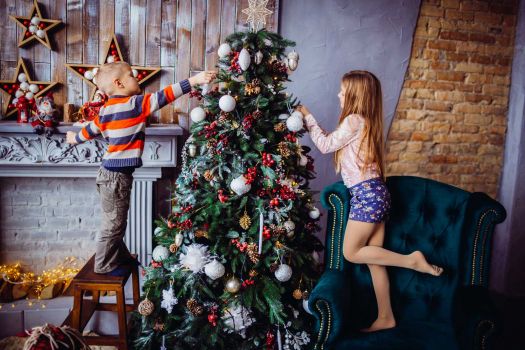 Zwei kleine Kinder schmücken einen Weihnachtsbaum