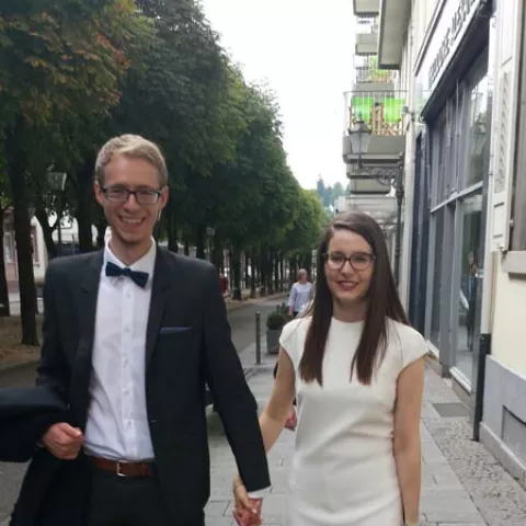 Ein gut gekleidetes Pärchen in einer Straße, während sie Händchen halten