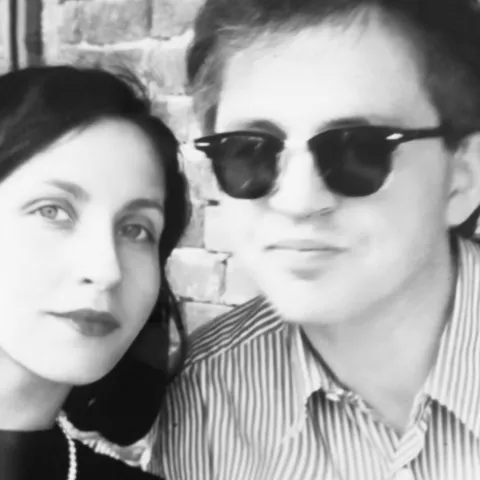 Ein Paar, welches nah aneinander sitzt und in die Kamera schaut