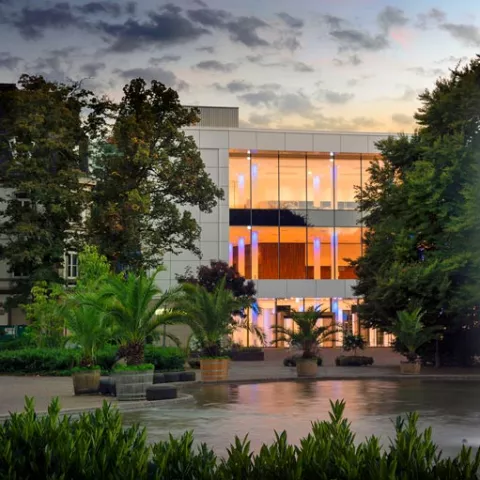 Modernes Kongresshaus mit einem Teich davor bei Dämmerung