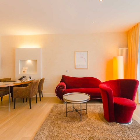 Geräumiges Wohnzimmer in einer Suite mit einem roten Sofa