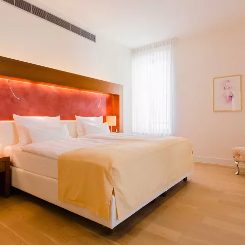 Großes beleuchtetes Doppelbett in einem Schlafzimmer