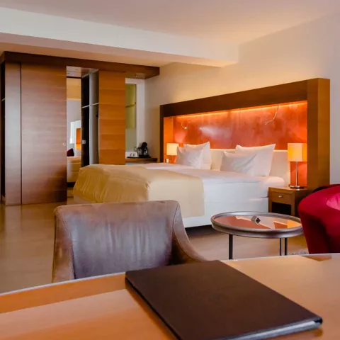 Foto eines roten Stuhls, eines roten Sofas und eines Doppelbetts in der Superior Suite 