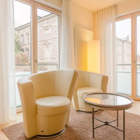 Weiße bequeme Hocker vor großen Fenstern