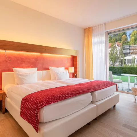 Detailansicht eines Doppelbetts mit roter Dekoration in der Superior-Suite