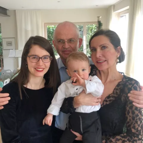 Ein Mann und zwei Frauen, wie sie ein Baby halten und in die Kamera lachen