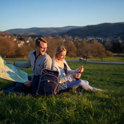 Ein Pärchen sitzt aneinander gelehnt auf einer Picknickdecke und genießt den Ausblick