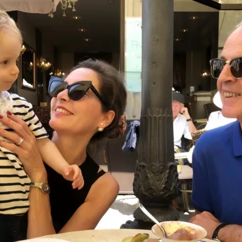 Eine Frau und ein Mann, die ein Baby halten und dieses anlächeln