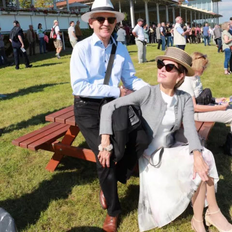 Ein Paar, dass auf einer Bank sitzt mit mehreren Menschen im Hintergrund