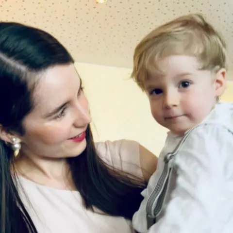 Eine Frau hält einen kleinen Jungen auf dem Arm und schaut diesen an