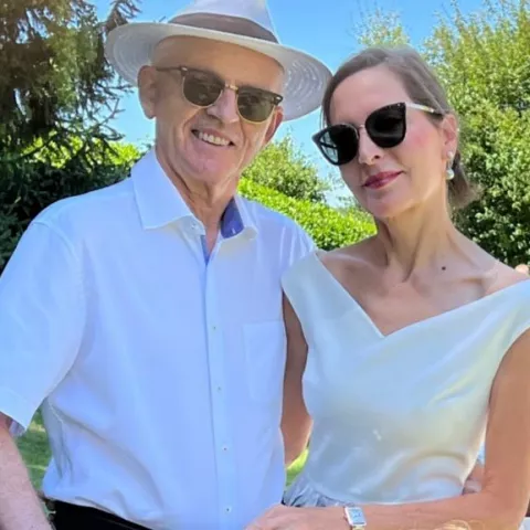 Ein älteres Pärchen in eleganter Kleidung das in die Kamera lächelt