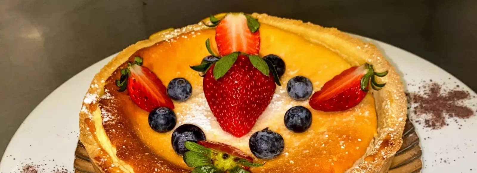 Detailaufnahme eines mit Früchten dekorierten Törtchens